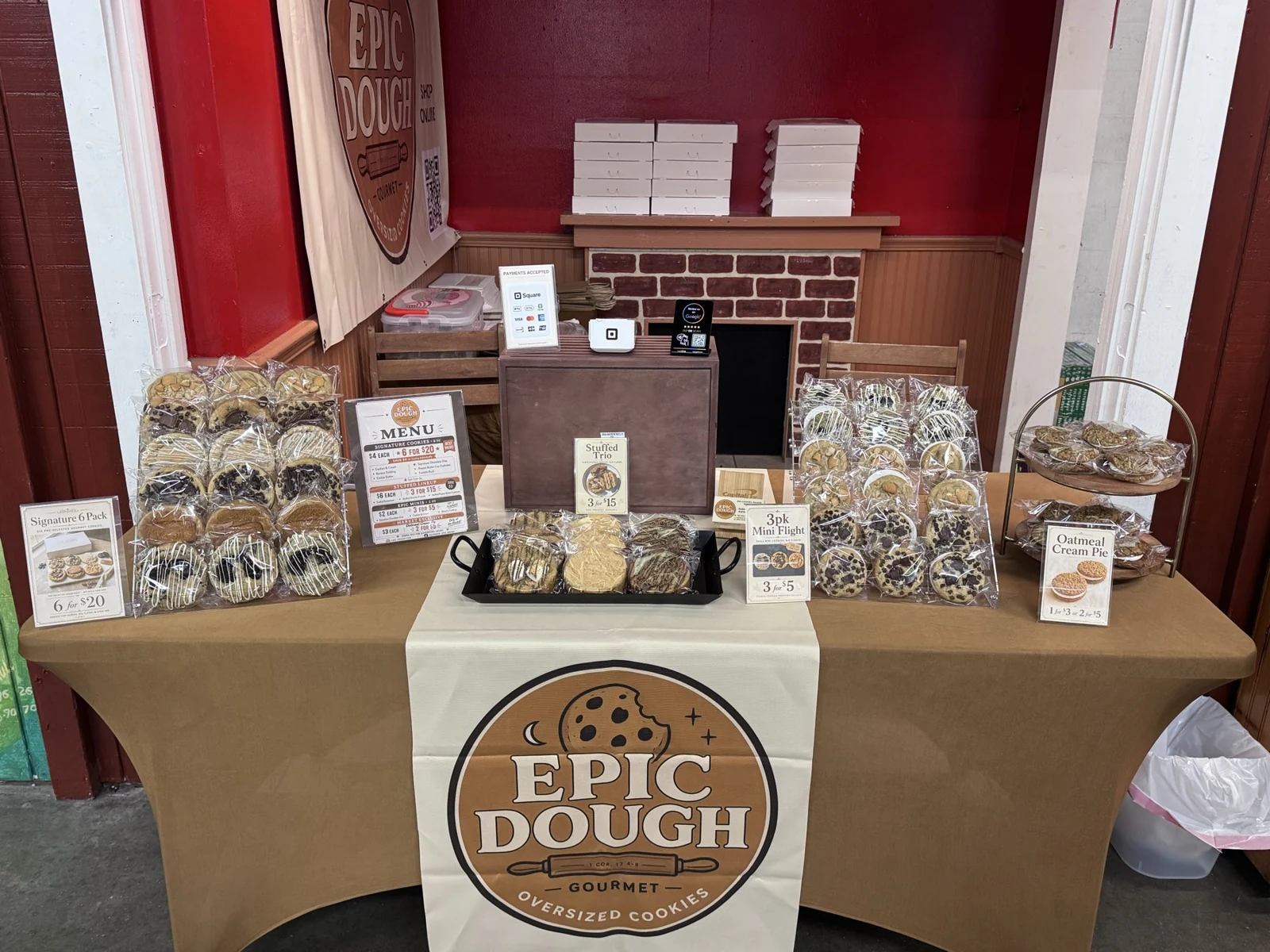 The Epic Dough market table, with packaged cookies, a tiered stand and printed menu cards.